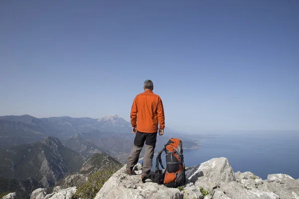 Un viajero se para en la cima de una montaña y mira hacia el mar . — Foto de Stock