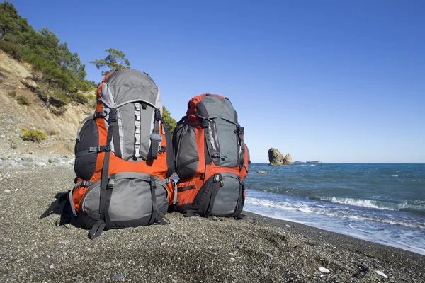 Mochilas estão na praia nas montanhas de fundo . — Fotografia de Stock