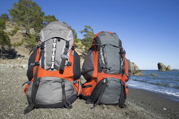 Ryggsäckarna är på stranden i bakgrunden bergen. — Stockfoto