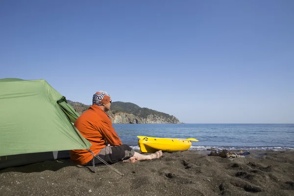 Un uomo si siede in un campo tenda sulla spiaggia . — Foto Stock