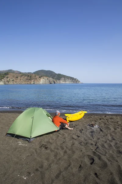 En man sitter i ett tältläger på stranden. — Stockfoto