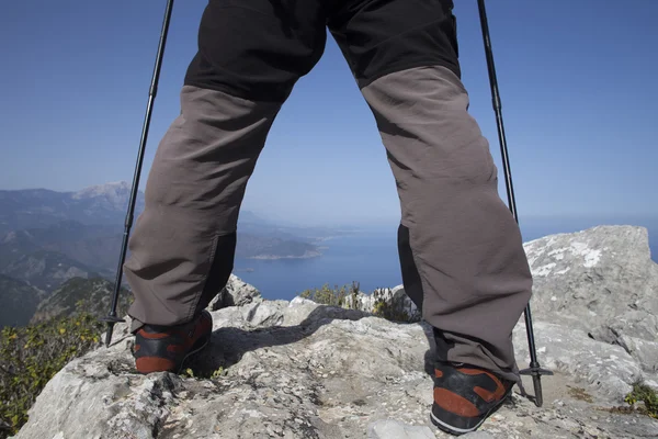 Een reiziger staat op de top van een berg en kijkt uit naar zee. — Stockfoto