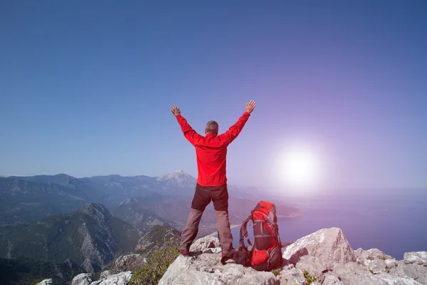 Un viajero se para en la cima de una montaña y mira hacia el mar . —  Fotos de Stock