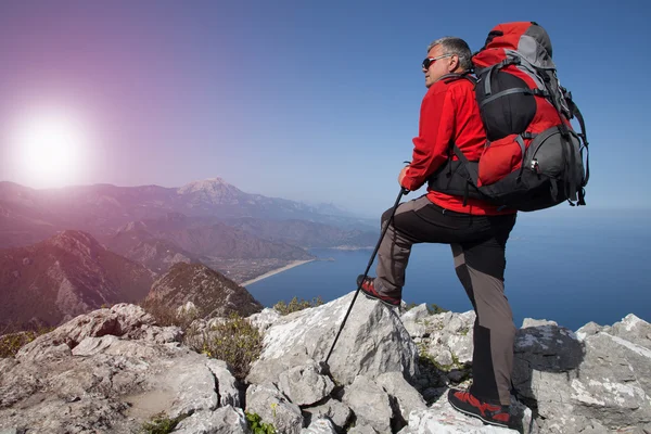 Un viajero se para en la cima de una montaña y mira hacia el mar . —  Fotos de Stock