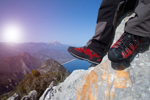 Un voyageur se tient au sommet d'une montagne et regarde vers la mer . — Photo