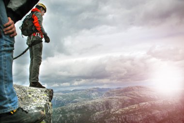 Young man jumping from a cliff into the abyss. clipart