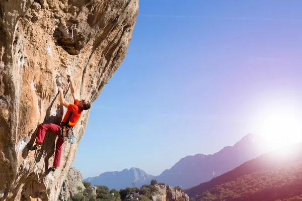 Athlete climbs on a rock against mountains. — Stock Photo, Image