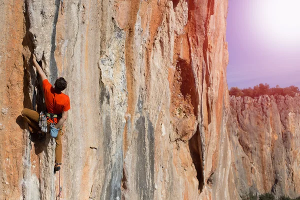Idrottsman klättrar på en sten mot bergen. — Stockfoto