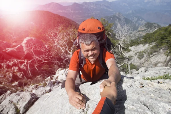 Senderistas escalando en roca, montaña al atardecer, uno de ellos dando la mano y ayudando a escalar . — Foto de Stock