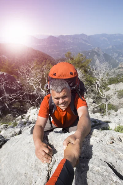 Escursionisti arrampicata su roccia, montagna al tramonto, uno di loro dando mano e aiutando a scalare . — Foto Stock