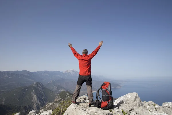 Un voyageur se tient au sommet d'une montagne et regarde vers la mer . — Photo