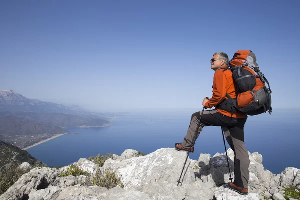 Un viajero se para en la cima de una montaña y mira hacia el mar . — Foto de Stock