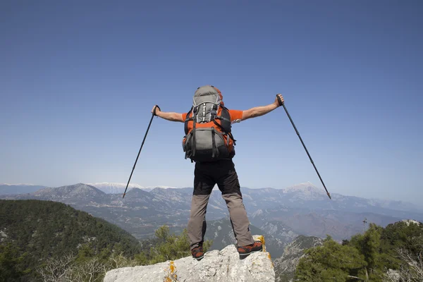 En resenär står på toppen av ett berg och ser till havet. — Stockfoto