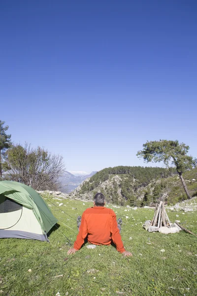 Bir gezgin bir dağın tepesinde duruyor ve denize bakıyor.