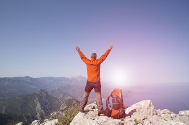 Bir gezgin bir dağın tepesinde duruyor ve denize bakıyor.