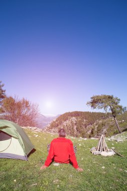 Bir gezgin bir dağın tepesinde duruyor ve denize bakıyor.