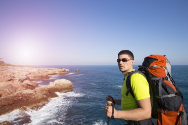 Bir gezgin bir dağın tepesinde duruyor ve denize bakıyor.