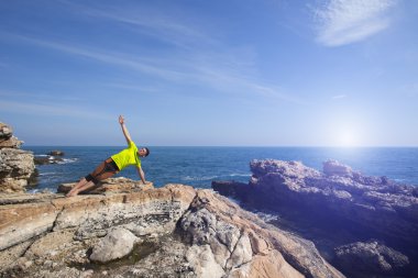 Genç adam plajda yoga yapıyor..