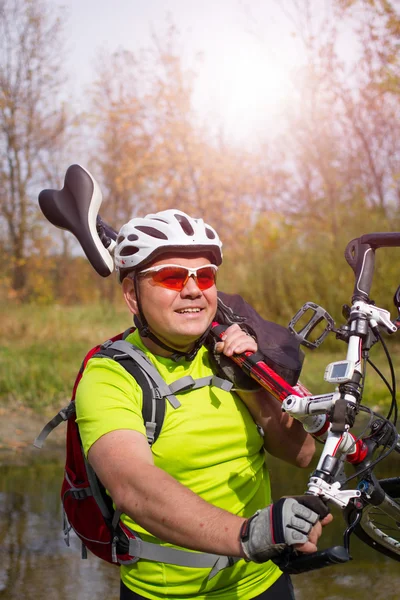 Young athlete crossing rocky terrain with bicycle in his hands. — Stock Photo, Image