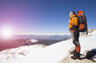 Bir gezgin bir dağ ve güneşin doğuşunu izlemek üstünde duruyor.