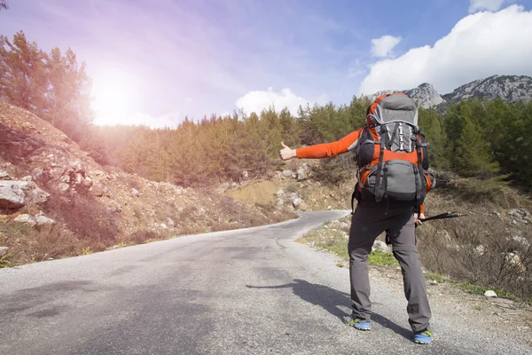 Hitchhiking traveler try to stop car on the mountain road — Stock Photo, Image