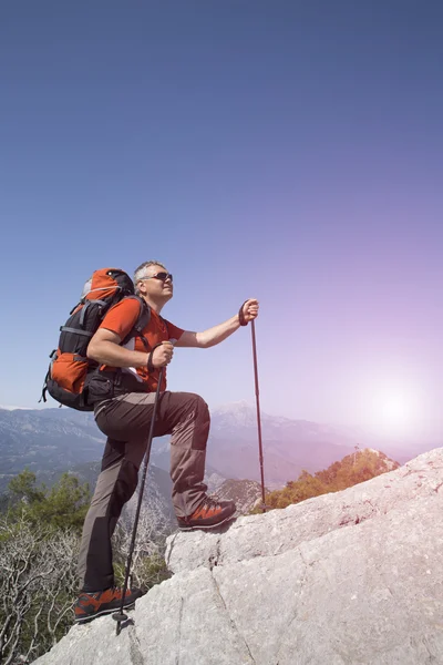 En resenär står på toppen av ett berg och ser till havet. — Stockfoto