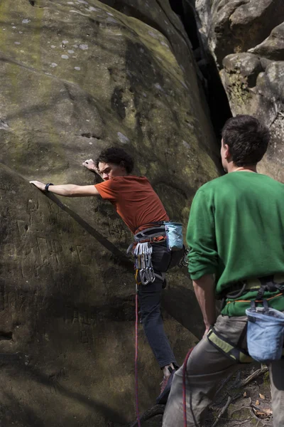 Young man climbs on a cliff with a rope. — Stock Photo, Image