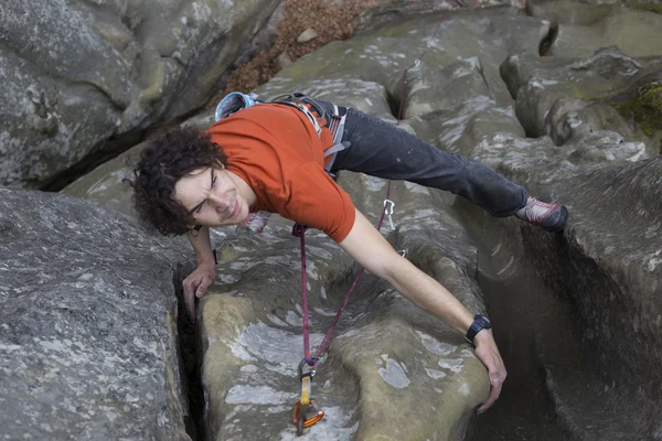 Jeune homme monte sur une falaise avec une corde . — Photo