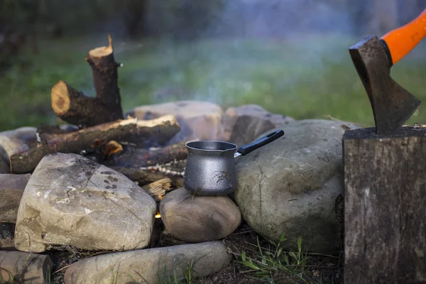 Camping.Girl sitting near a campfire at the campsite looking at map and drinking coffee. — Stock Photo, Image