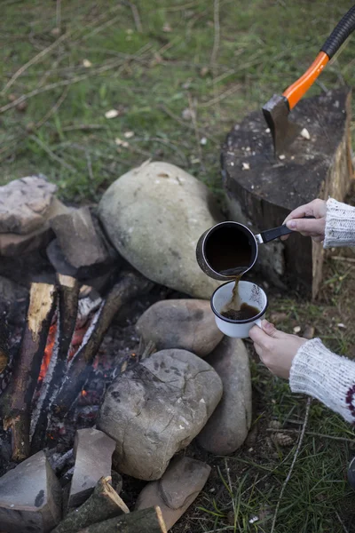 Ragazza seduta vicino a un falò al campeggio guardando la mappa e bevendo caffè . — Foto Stock