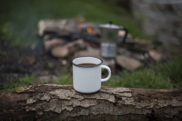 The cup stands on a log on the fire background. — Stock Photo, Image