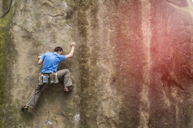 Atlet kaya iple tırmanıyor.