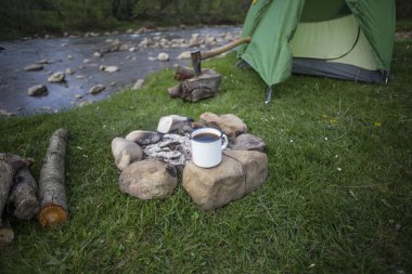 Kupa bir günlük bir kamp ateşi yanında duruyor.