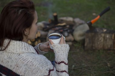 Bir kız tarafından yangın ve içecek kahve oturuyor.