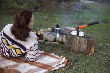 Bir kız tarafından yangın ve içecek kahve oturuyor.