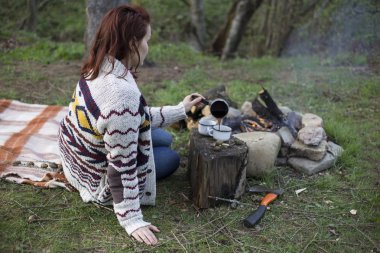 Bir kız tarafından yangın ve içecek kahve oturuyor.