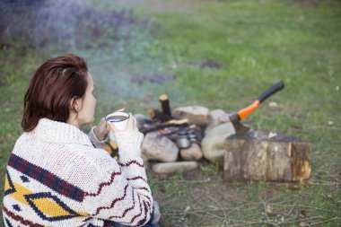 Bir kız tarafından yangın ve içecek kahve oturuyor.