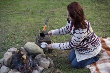 Bir kız tarafından yangın ve içecek kahve oturuyor.