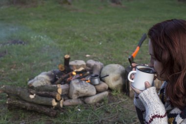 Bir kız tarafından yangın ve içecek kahve oturuyor.