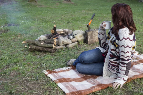 Bir kız tarafından yangın ve içecek kahve oturuyor.