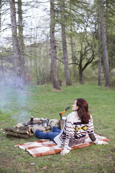 Bir kız tarafından yangın ve içecek kahve oturuyor.