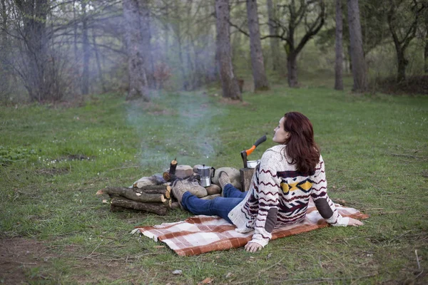 Bir kız tarafından yangın ve içecek kahve oturuyor.