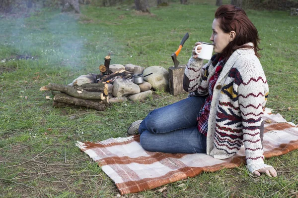 Bir kız tarafından yangın ve içecek kahve oturuyor.