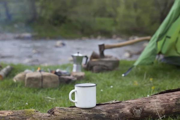 Mug stands on a log near the fire at a campsite. — Stock Photo, Image