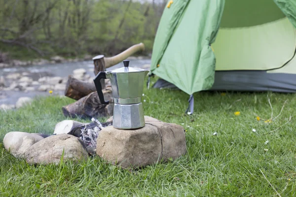 Tazza si trova su un tronco vicino al fuoco in un campeggio . — Foto Stock