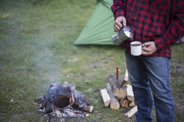 Ateşin yanında kahve içme adam.