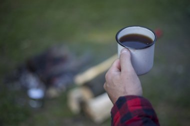 Ateşin yanında kahve içme adam.