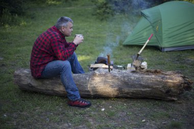 Ateşin yanında kahve içme adam.