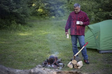Ateşin yanında kahve içme adam.