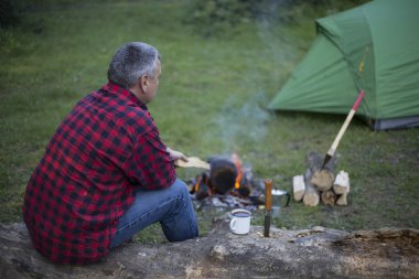 Ateşin yanında kahve içme adam.